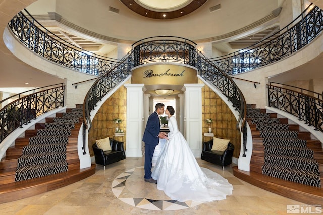 stairs with tile flooring, a high ceiling, and decorative columns