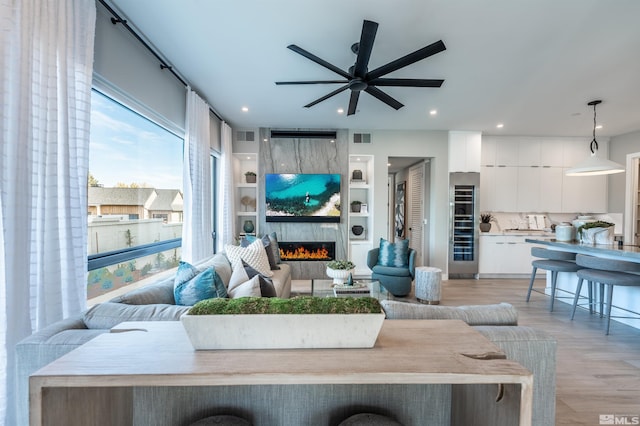 living room with ceiling fan, light wood-type flooring, and a fireplace