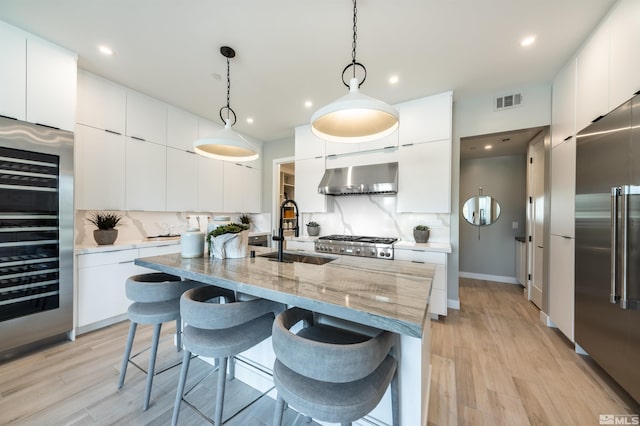 kitchen featuring white cabinets, tasteful backsplash, and wall chimney exhaust hood