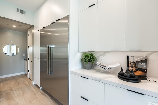 kitchen with high end refrigerator, white cabinets, and light wood-type flooring