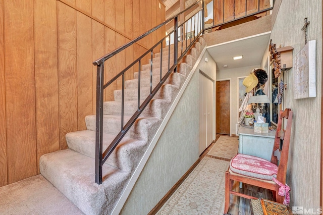 stairway featuring carpet floors and wood walls