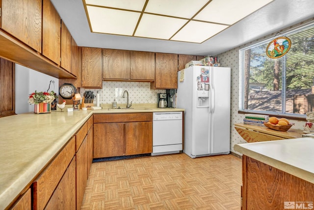 kitchen with white appliances, sink, and light parquet flooring