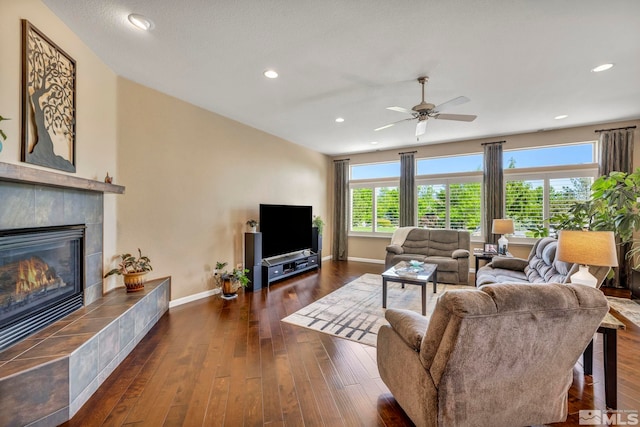 living room with ceiling fan, a tile fireplace, and dark hardwood / wood-style flooring