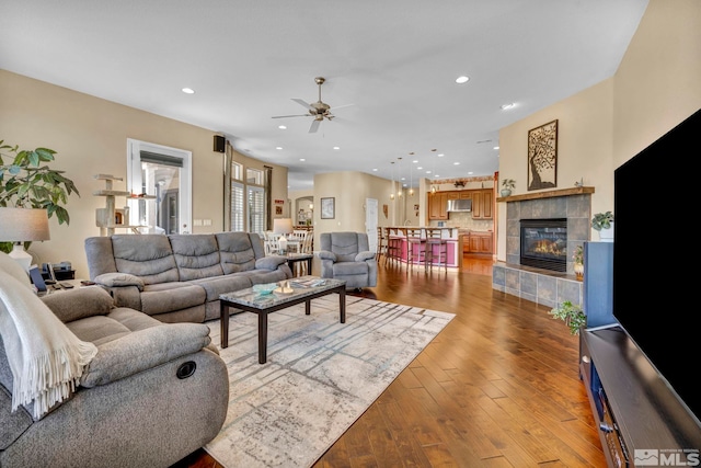 living room with ceiling fan, light hardwood / wood-style floors, and a fireplace