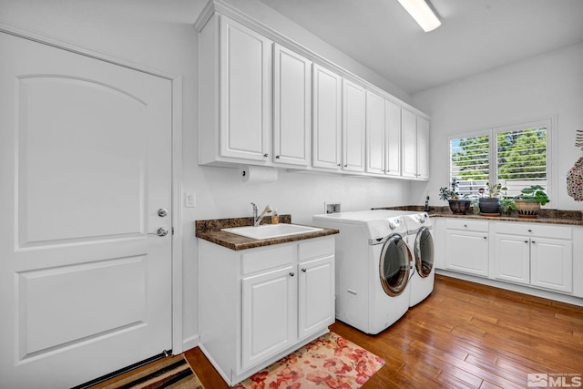 laundry room with light hardwood / wood-style flooring, washing machine and clothes dryer, hookup for a washing machine, sink, and cabinets