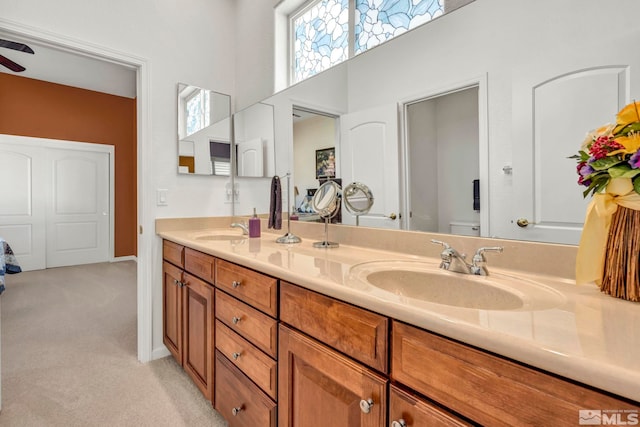 bathroom with dual vanity, a high ceiling, and ceiling fan