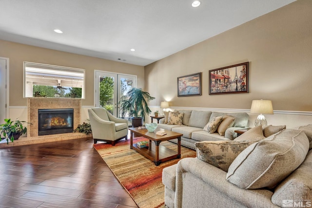 living room featuring a tiled fireplace and dark wood-type flooring