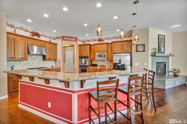 kitchen featuring backsplash, appliances with stainless steel finishes, a fireplace, and pendant lighting