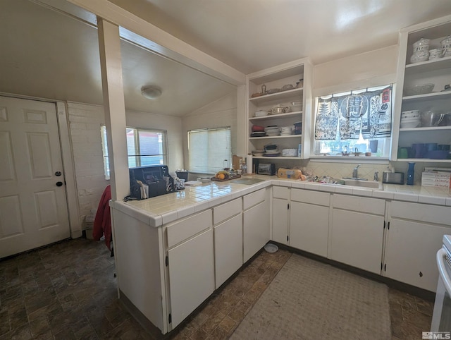 kitchen featuring lofted ceiling, tile counters, white cabinets, range, and dark tile flooring