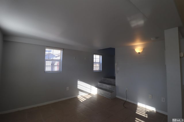 empty room featuring a healthy amount of sunlight and dark tile floors