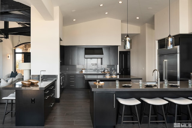 kitchen with high vaulted ceiling, stainless steel built in refrigerator, sink, and tasteful backsplash