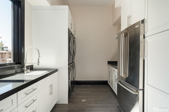 kitchen featuring sink, high end refrigerator, white cabinetry, and stacked washer and clothes dryer