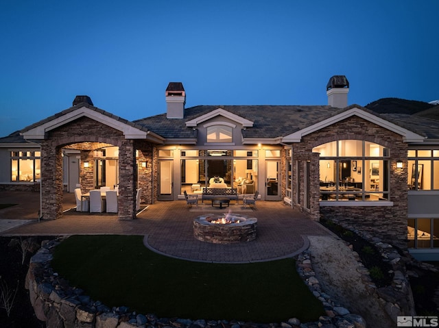 back house at night with a fire pit and a patio