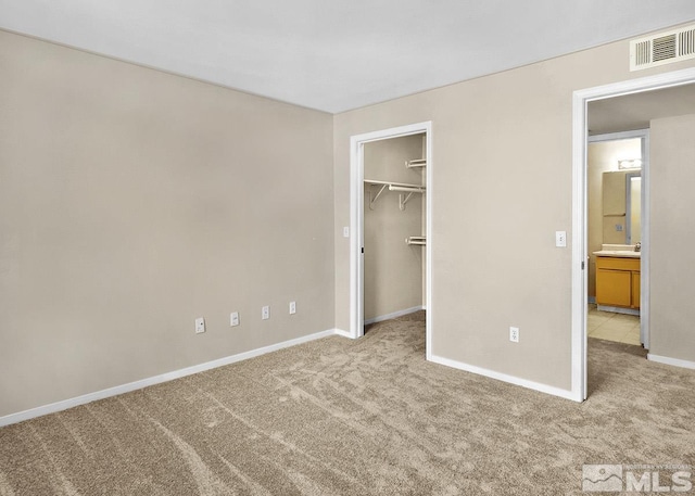 unfurnished bedroom with a closet, light carpet, and a spacious closet