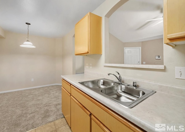 kitchen with light brown cabinets, decorative light fixtures, ceiling fan, light carpet, and sink