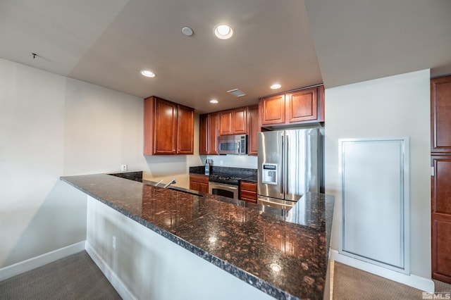 kitchen featuring carpet flooring, kitchen peninsula, stainless steel appliances, and dark stone counters