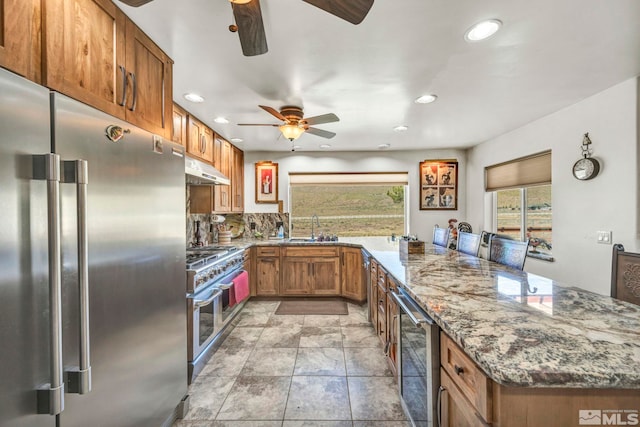 kitchen with stone counters, ceiling fan, appliances with stainless steel finishes, sink, and light tile floors