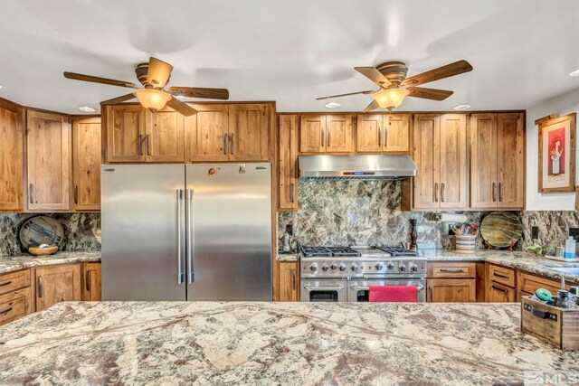 kitchen featuring light stone countertops, tasteful backsplash, premium appliances, and ceiling fan