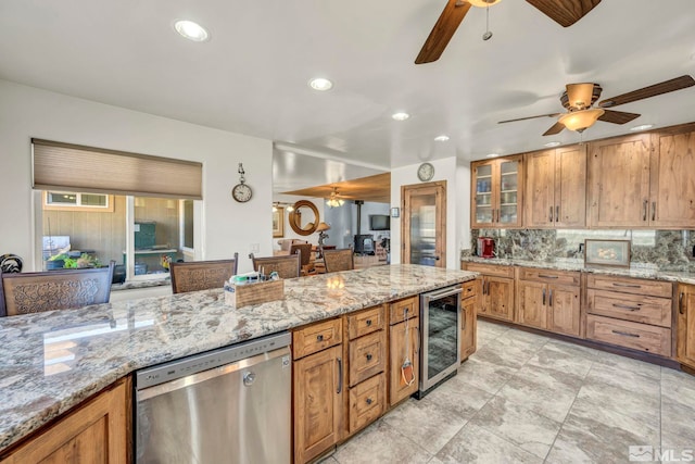 kitchen with wine cooler, ceiling fan, light stone countertops, stainless steel dishwasher, and backsplash