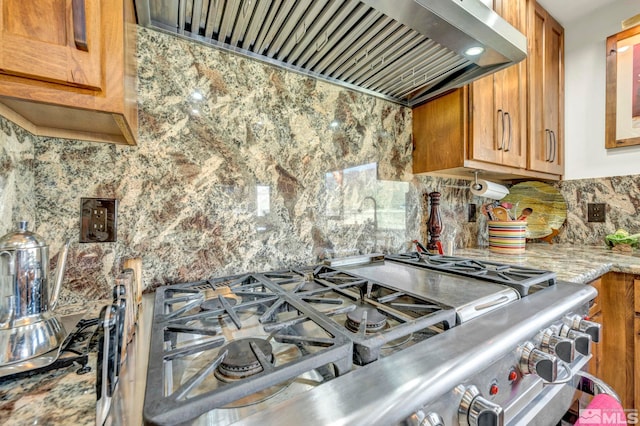 kitchen featuring stainless steel range, premium range hood, backsplash, and light stone countertops