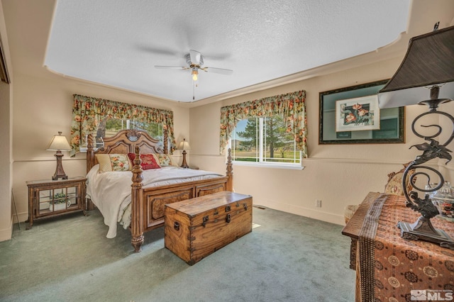 bedroom featuring a raised ceiling, carpet, ceiling fan, and a textured ceiling