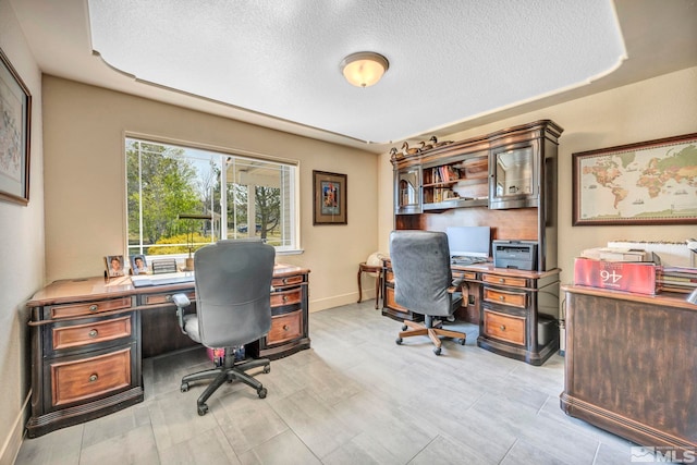 office space featuring a tray ceiling, built in desk, a textured ceiling, and light tile flooring