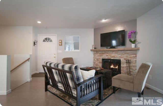 living room with a stone fireplace and concrete flooring