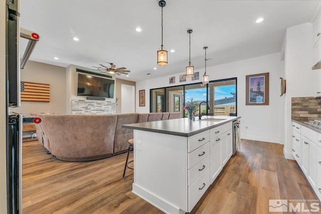 kitchen with white cabinetry, sink, an island with sink, and light wood-type flooring