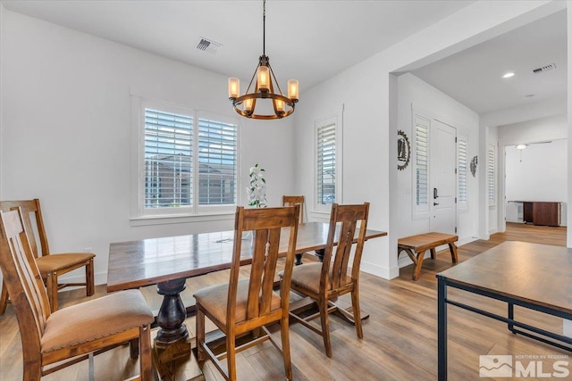 dining room with light wood-type flooring and an inviting chandelier