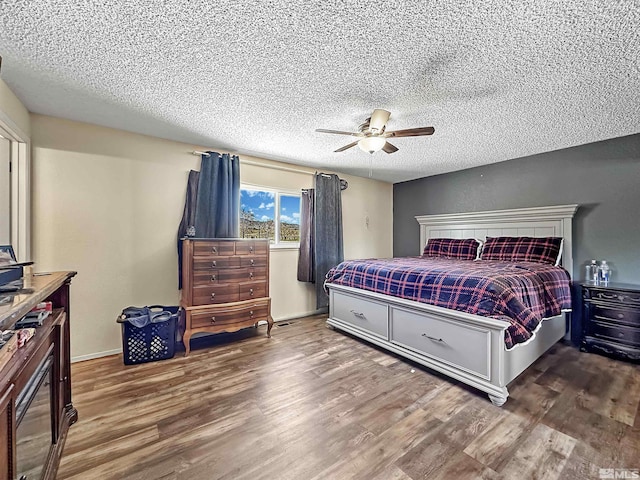 bedroom with a textured ceiling, ceiling fan, and dark wood-type flooring