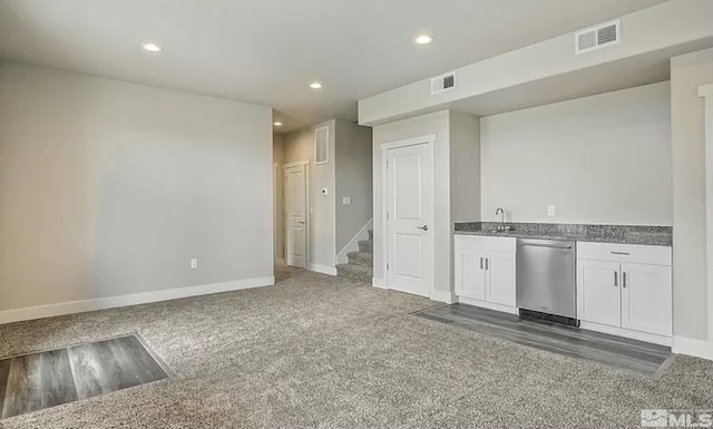 kitchen featuring white cabinets, dark colored carpet, stainless steel dishwasher, and sink