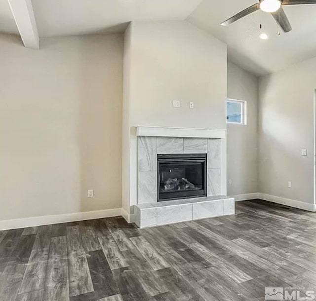 unfurnished living room featuring a tiled fireplace, ceiling fan, dark hardwood / wood-style floors, and vaulted ceiling with beams