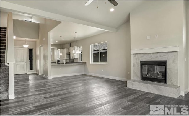 unfurnished living room with ceiling fan, dark wood-type flooring, and a premium fireplace