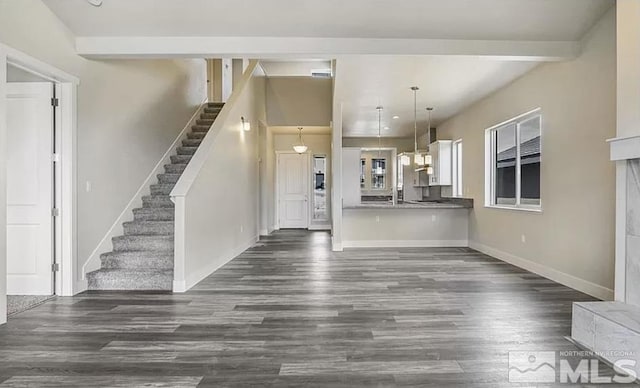 unfurnished living room featuring beam ceiling and dark hardwood / wood-style flooring