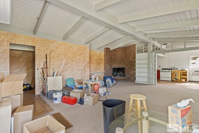 living room featuring brick wall, vaulted ceiling with beams, a large fireplace, and carpet flooring