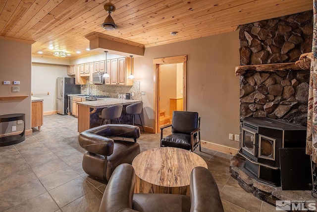 tiled living room with ornamental molding, a wood stove, and wood ceiling