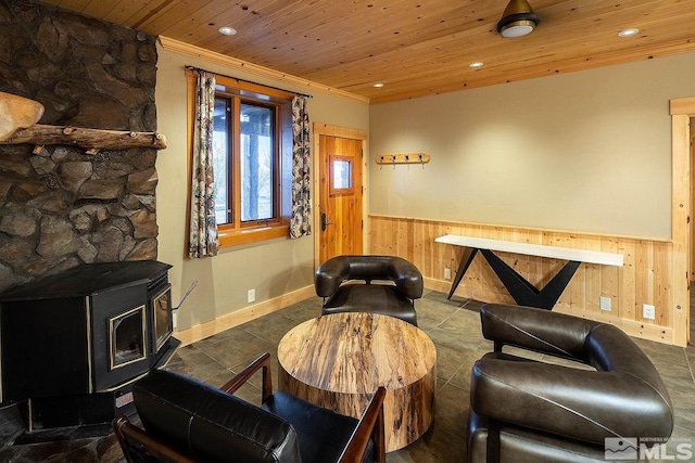 living area with a wood stove, wooden ceiling, wooden walls, and dark tile patterned flooring