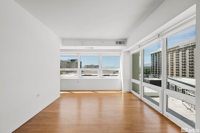 empty room with visible vents, a view of city, and wood finished floors