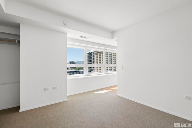 carpeted spare room with visible vents, a city view, and baseboards