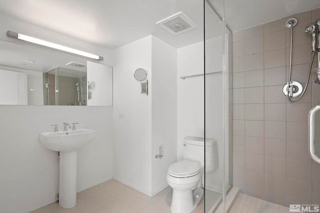 bathroom featuring visible vents, baseboards, toilet, a stall shower, and a sink