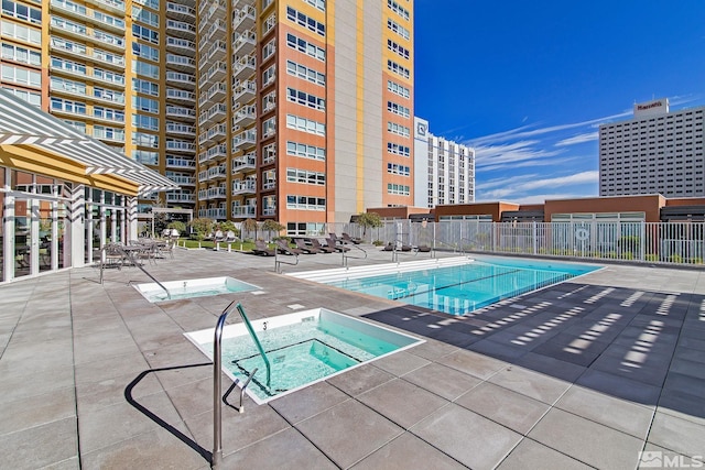 community pool featuring a patio, fence, and a hot tub