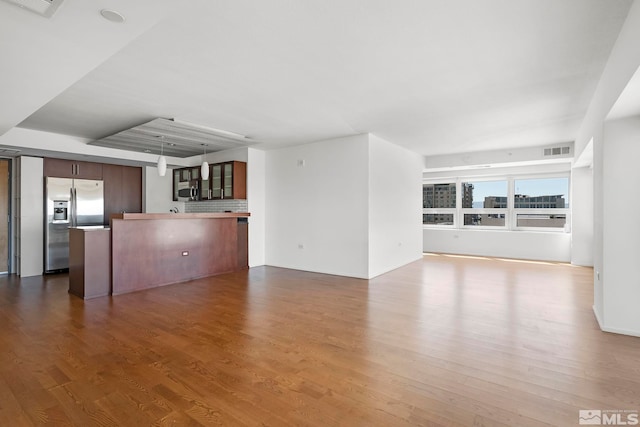 unfurnished living room featuring visible vents and wood finished floors