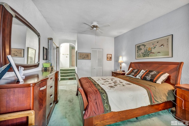 bedroom featuring ceiling fan, a closet, carpet floors, and a textured ceiling