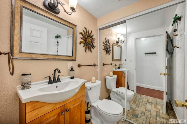 bathroom featuring vanity, a textured ceiling, and toilet