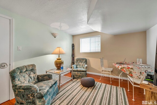 sitting room featuring hardwood / wood-style flooring, a textured ceiling, and vaulted ceiling