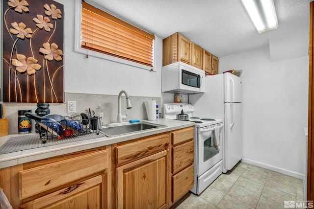 kitchen with white appliances, sink, light tile patterned floors, a textured ceiling, and tile counters