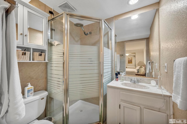 bathroom with a shower with door, vanity, and toilet