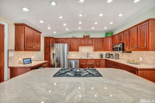 kitchen featuring light stone countertops, sink, vaulted ceiling, decorative backsplash, and appliances with stainless steel finishes