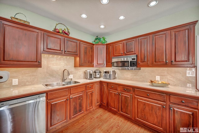 kitchen featuring sink, tile counters, stainless steel appliances, light hardwood / wood-style flooring, and decorative backsplash