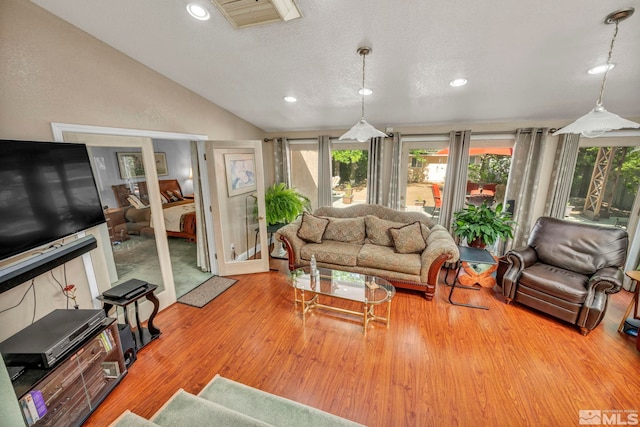 living room with a textured ceiling, light hardwood / wood-style flooring, and lofted ceiling